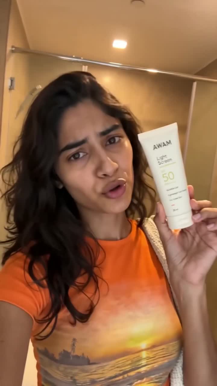 A creator holds up a sunscreen tube on camera, talking to the lens