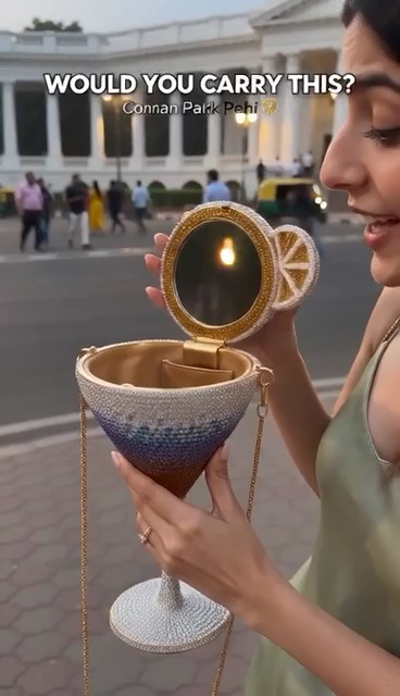 A woman carrying a jeweled cocktail-glass bag on a city street